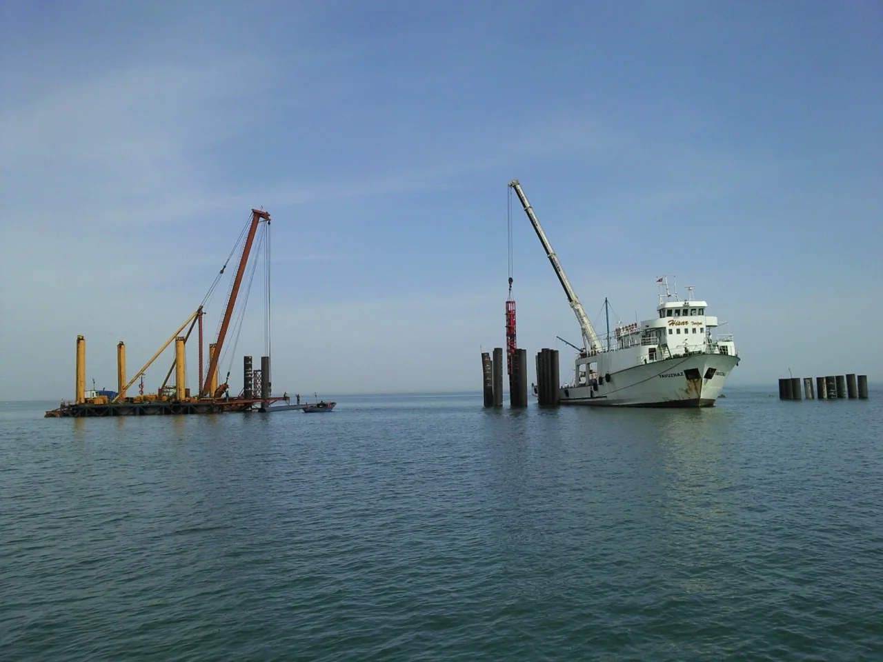 Work vessel and marine equipment alongside dolphin piles